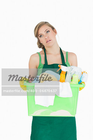 Tied young maid carrying cleaning supplies over white background