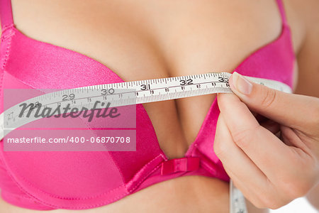 Extreme closeup of woman measuring chest in pink bra