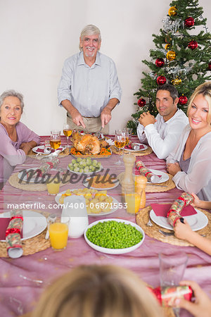 Happy grandfather carving the christmas turkey at the dinner table