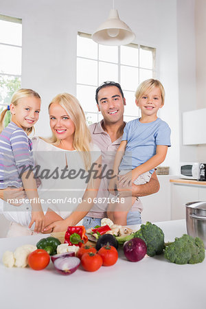 Smiling parents bearing their offspring in the kitchen