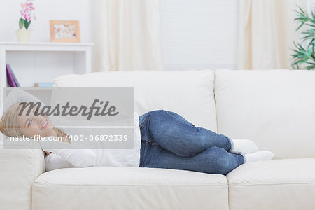 Portrait of casual young woman lying on sofa at home