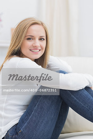 Portrait of casual happy young woman sitting on sofa at home