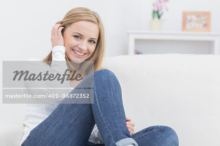 Portrait of casual happy young woman sitting on sofa at home