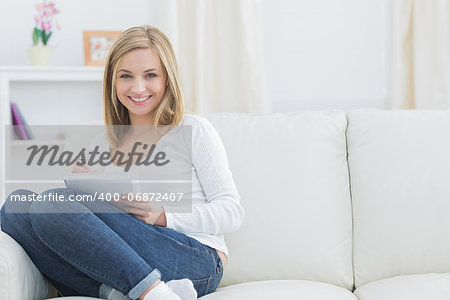 Portrait of happy young woman with notepad and pen on couch at home