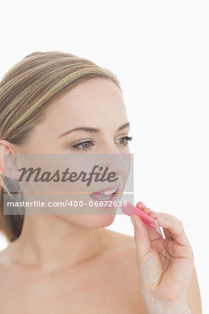 Closeup of young woman applying lipgloss over white background