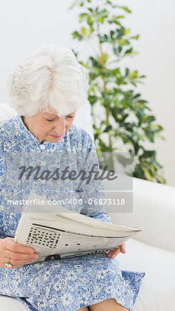 Elderly cheerful woman reading newspapers on the sofa