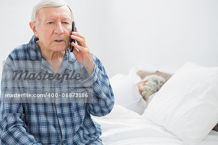 Old man on the phone sitting on the bed