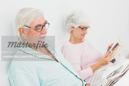 Old husband and wife reading in bed