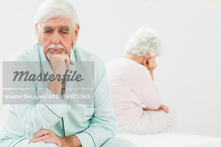 Sad elderly husband not talking to wife in bedroom