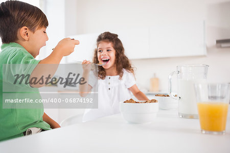 Two children eating cereal in kitchen