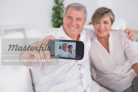 Old man taking a photo of him and his wife with a smartphone