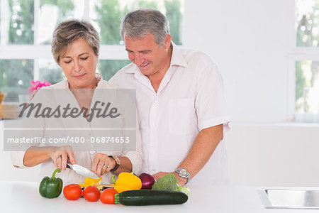 Old couple preparing vegetables in kitchen
