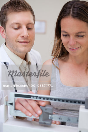 Doctor helping patient to adjust medical scale