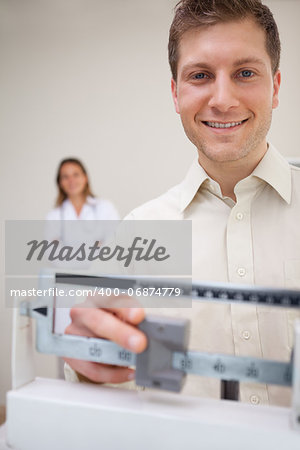 Smiling man adjusting scale with doctor behind him