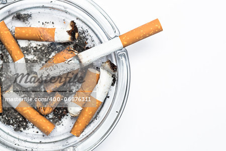 Overhead of burning cigarette in ashtray with copy space on white background