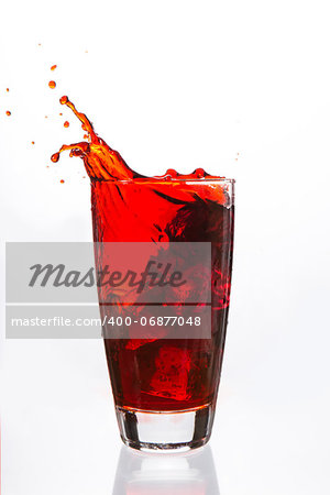 Ices cubes falling in a glass filled with red liquid on white background