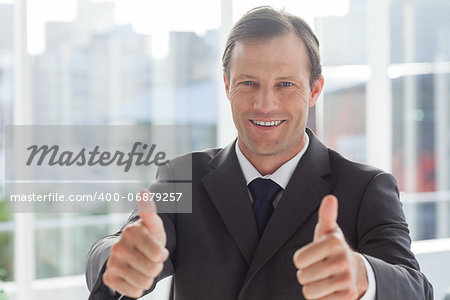 Smiling businessman giving thumbs up in an office