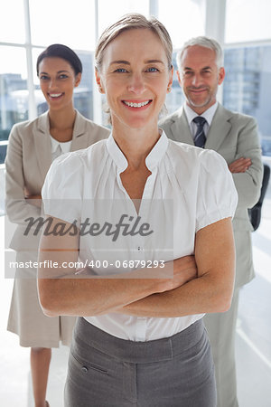 Cheerful team of business people standing together with their arms crossed