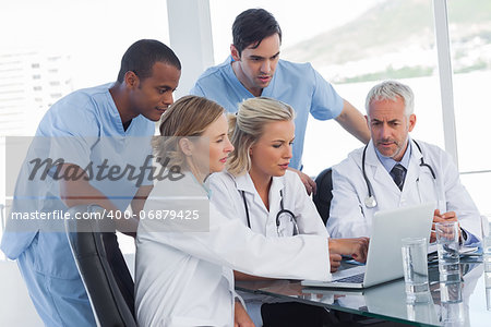 Serious medical team using a laptop in a bright office