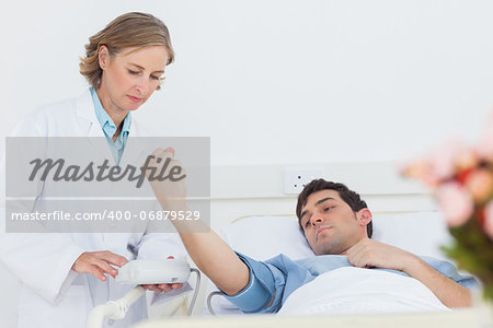 Woman doctor taking the blood pressure of male patient in a hospital