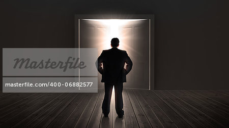 Businessman watching doors opening to a bright light in the shadows