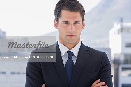 Businessman standing with arms crossed in a bright office