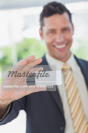 Happy businessman showing a white business card in office