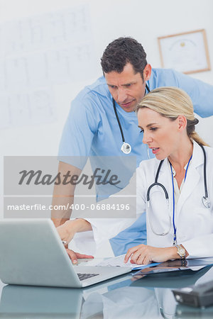 Blonde woman showing something on a laptop to her colleague in a medical office