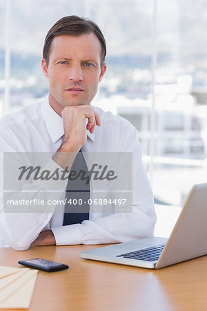 Handsome businessman posing in his office sitting next to his desk