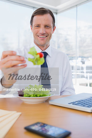 Cheerful businessman eating a salad during the lunch time