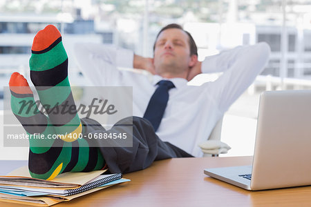Businessman sleeping with feet without shoes on his desk