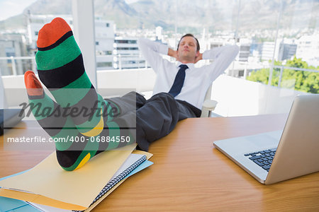 Business having a nap with feet over a pile of documents on his desk