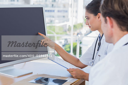 Doctor pointing at the screen of a computer while working with a colleague