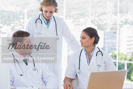 Group of doctors discussing and working together with a laptop