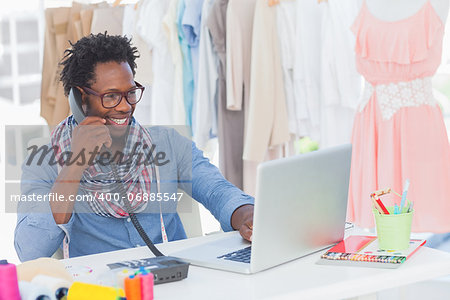 Attractive fashion designer speaking on the phone in a creative office