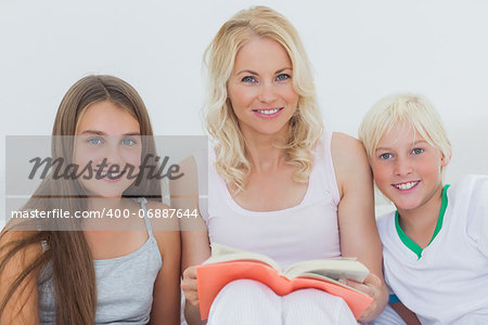 Portrait of mother holding a storybook to her happy children