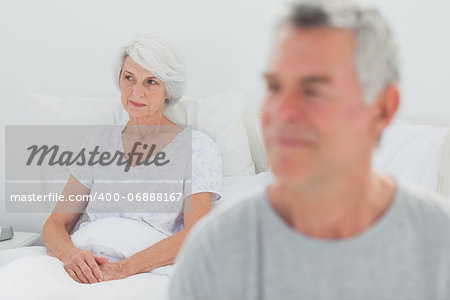 Mature man sulking in bed during a conflict with wife