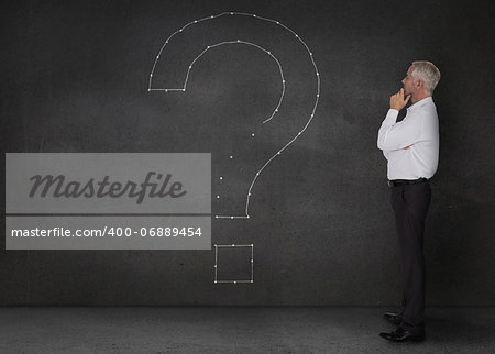 Elegant businessman looking at a giant question mark drawn on the wall