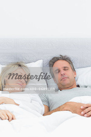 Couple sleeping soundly in their bed at home in bedroom