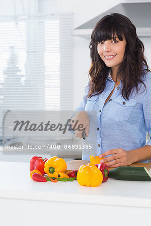 Pretty brunette slicing pepper at kitchen counter