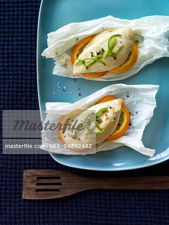 Parchment Paper Packets of Steamed Chicken Breast with Oranges, Black Pepper and Sliced Green Pepper, Studio Shot Parchment Paper Packets of Steamed Chicken Breast with Oranges, Black Pepper and Sliced Green Pepper, Studio Shot