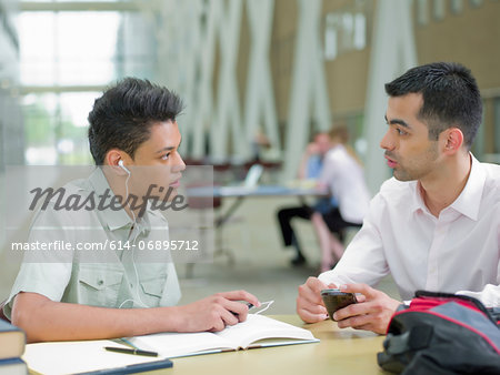 Young man studying with mid adult tutor