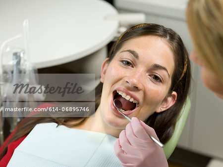 Dentist examining young woman's teeth