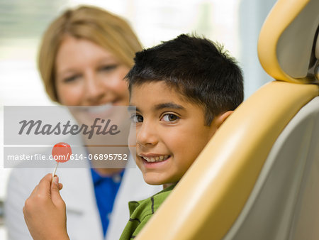Young boy holding lollipop at the dentist's office, portrait