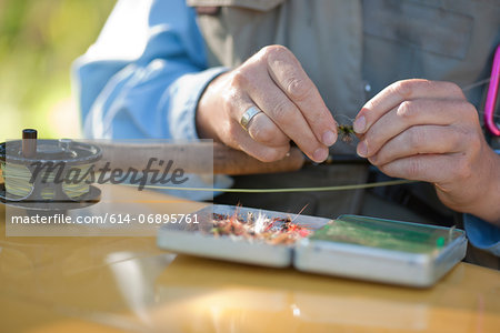 Mature woman preparing bait for fly fishing, close up