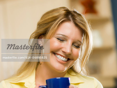 Mid adult woman holding cup and laughing