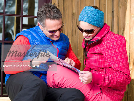 Mature man and young woman looking at map in ski resort