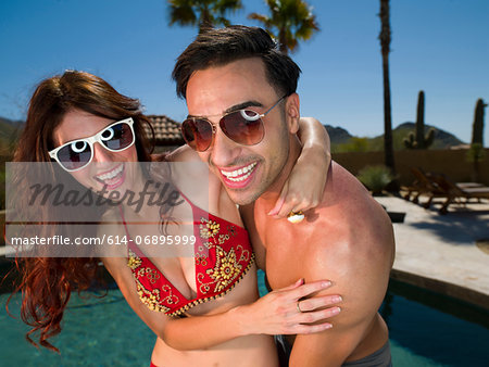 Young couple embracing at poolside, smiling