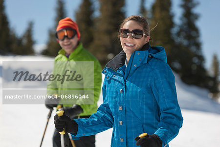 Young woman in skiwear holding ski poles, portrait