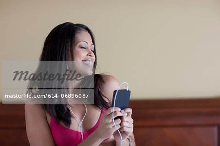 Young woman listening to music from mp3 player, smiling